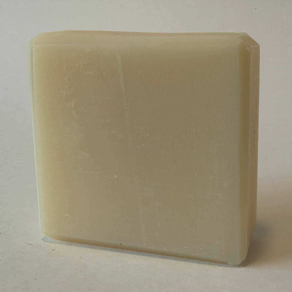 A rectangular bar of creamy off-white soap standing upright on a plain light background.