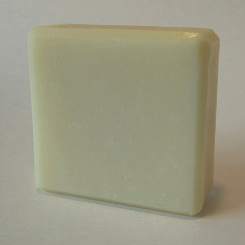 A rectangular bar of creamy off-white soap standing upright on a plain light background.