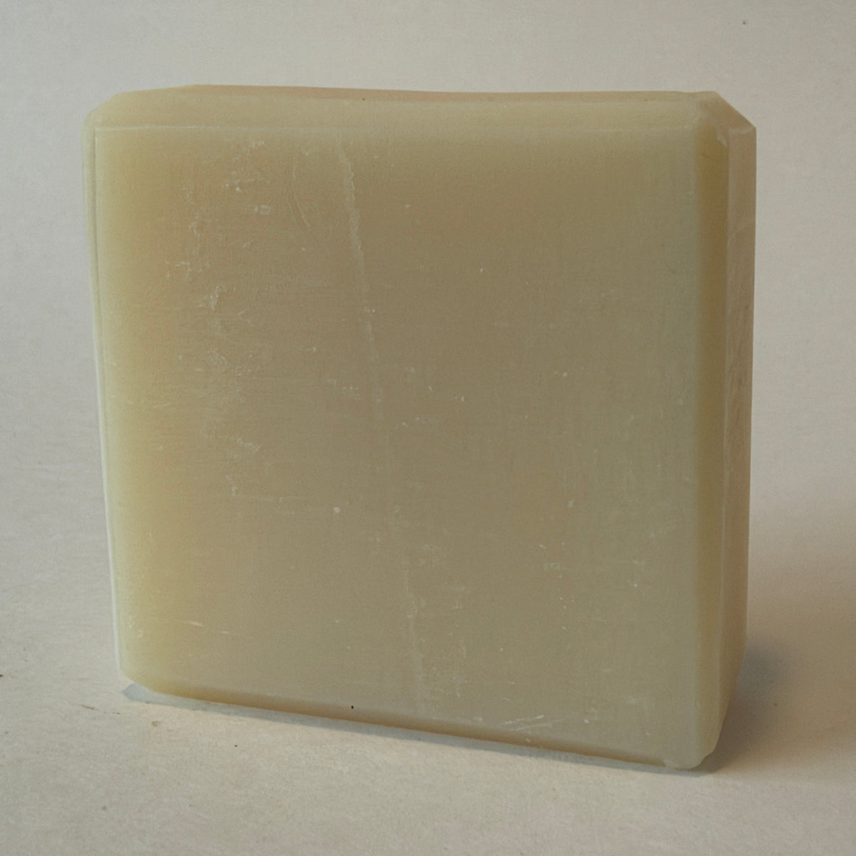 A rectangular bar of creamy off-white soap standing upright on a plain light background.